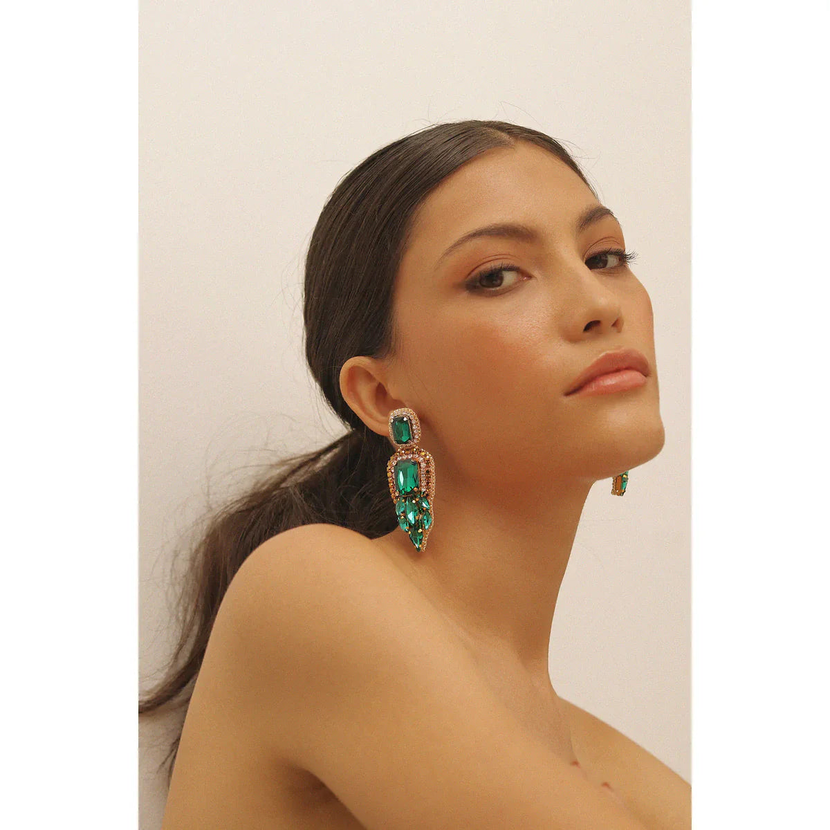A brunette model showing us how to wear emerald with two earring that make her look elegant