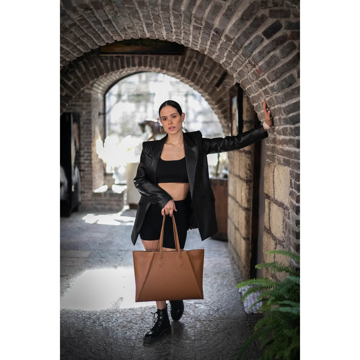 A model in a black monochromatic outfit showing how to style handbags with a coffee tote bag in OnPost