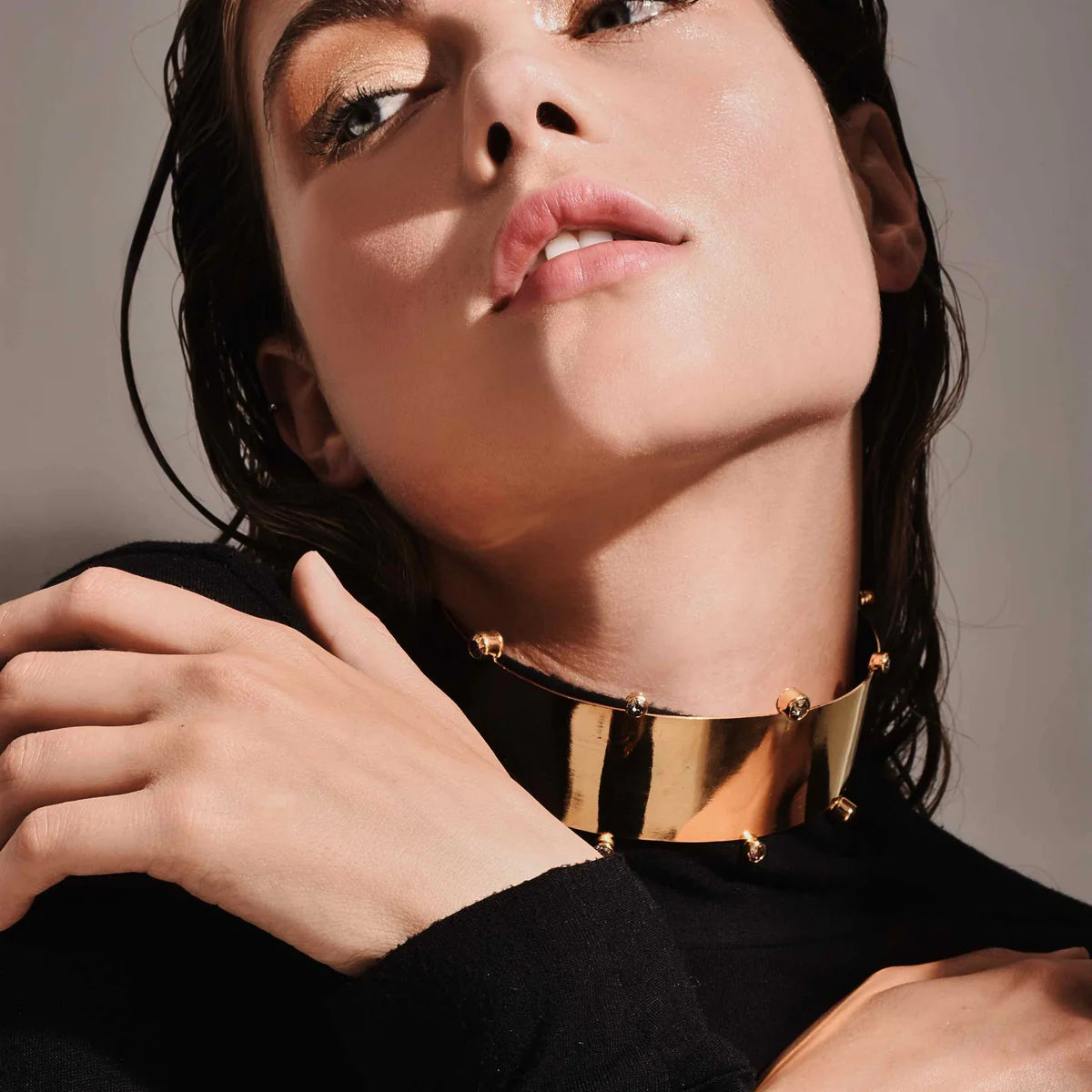 a brunette model showing us how to style a gold choker with a black sweater with OnPost